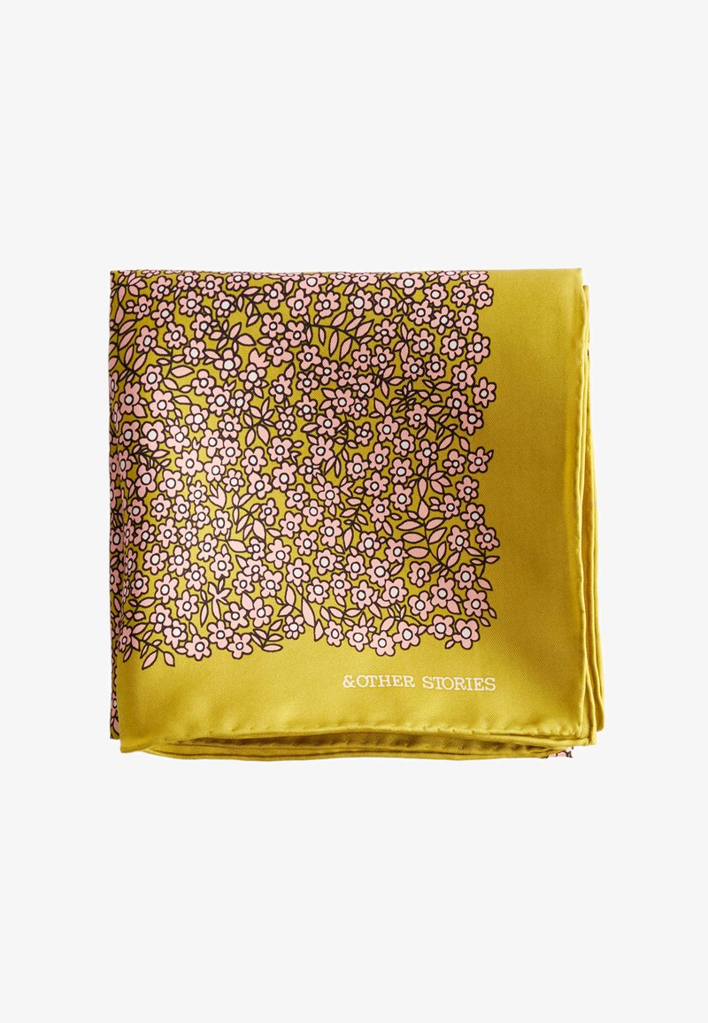 Écharpe jaune pliée avec un motif floral rose dense et des feuilles vertes, marquée du texte blanc "&OTHER STORIES" dans un coin.