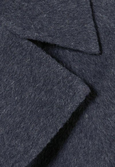 Tela de fieltro gris oscuro con dos puntas de cuello triangulares superpuestas. El material tiene una apariencia suave y texturizada con fibras visibles.