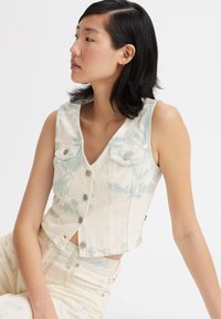 Cropped denim vest in off-white with blue tie-dye pattern, featuring a v-neck, two chest pockets, and button-down front.