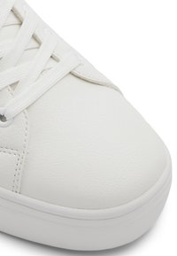 Sneaker bianca con tomaia in pelle liscia, punta rotonda e lacci bianchi piatti. Accentuata da una suola in gomma e dettagli di cucitura sottili.