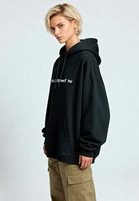 Hoodie nero oversize con tasca a marsupio, con la scritta bianca "Ho Pensato A Te" sul davanti. Maniche e orlo a costine, texture morbida.