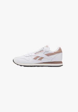Baskets basses blanches et beiges Reebok avec lacets sur le devant et semelle en caoutchouc, vues de profil sur fond blanc.