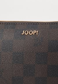 Braune strukturierte Brieftasche mit einem karierten Muster und goldenen "JOOP!"-Logo auf der Oberfläche, mit einem goldenen Reißverschluss entlang der oberen Kante.