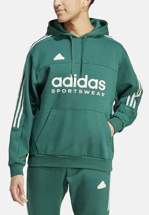 Sudadera de algodón verde con capucha, que presenta el texto blanco "adidas SPORTSWEAR" y tres rayas blancas en cada manga. Tiene un bolsillo tipo canguro en la parte delantera.