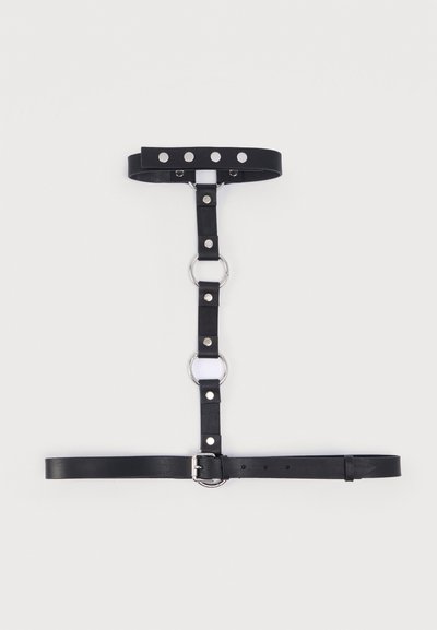 Μαύρο ιμιτασιόν δερμάτινο ζωνάρι με ασημένιες μεταλλικές κρίκους, κουμπώματα και ρυθμιζόμενους ιμάντες. Διαθέτει κεντρικό συνδετήρα και λεία, επίπεδη υφή.