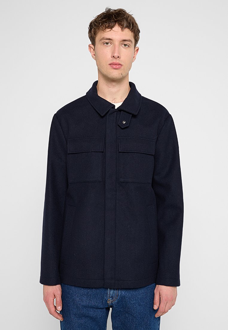 Marineblauer Wollmix-Jacke mit Kragen, zwei Brusttaschen und geknöpftem Frontverschluss. Hat einen geraden Schnitt und ein minimales Design.