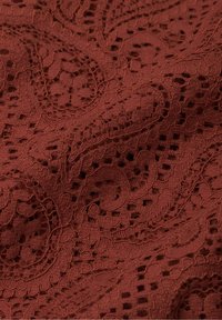 Tessuto di pizzo in un ricco colore ruggine, caratterizzato da intricati motivi floreali e elementi testurizzati, con un aspetto morbido e intrecciato.