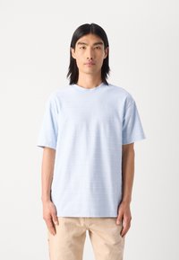 Lysblå kortærmet t-shirt med vandrette teksturmønstre, rund halsudskæring og løs pasform. Fremstillet af blødt bomuldsmateriale.