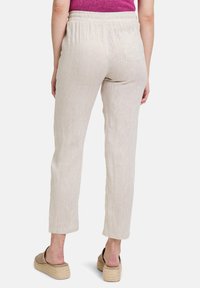 Lichtbeige linnen broek met een relaxte pasvorm, elastische tailleband en één achterzak. Rechtafstaande pijpen en minimale textuurdetails.