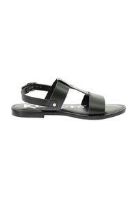 Sandalia de cuero negro con suela plana, que presenta dos correas anchas sobre el pie y una correa ajustable en el tobillo. Diseño simple y minimalista.