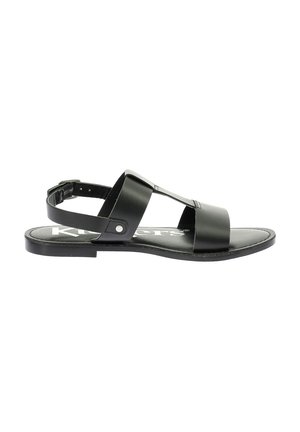 Sandale en cuir noir avec semelle plate, dotée de deux larges sangles sur le pied et d'une sangle de cheville réglable. Design simple et minimaliste.