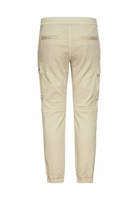 Pantalon cargo beige avec taille élastique et poignets, poches arrière passepoilées et poches latérales à rabat boutonné.