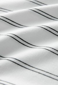 Hvidt stof med diskrete, vandrette sorte dobbelstriber, der viser bløde folder og tekstur i nærbillede.