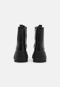 Bottines noires avec un extérieur en cuir lisse, des zips latéraux doubles et des semelles en caoutchouc épaisses et striées. Accent avec des tirettes à l'arrière.