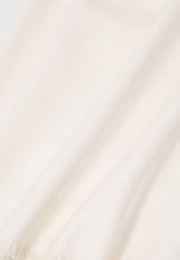 Bela pletena šal z mehkimi teksturami, ki vsebuje subtilen ribji vzorec in fru fru robove. Gladka in lahka tkanina.