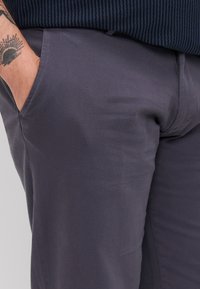 Gray tailored trousers featuring a smooth texture, side pockets, and a slim fit design. Fabric appears durable and lightweight.