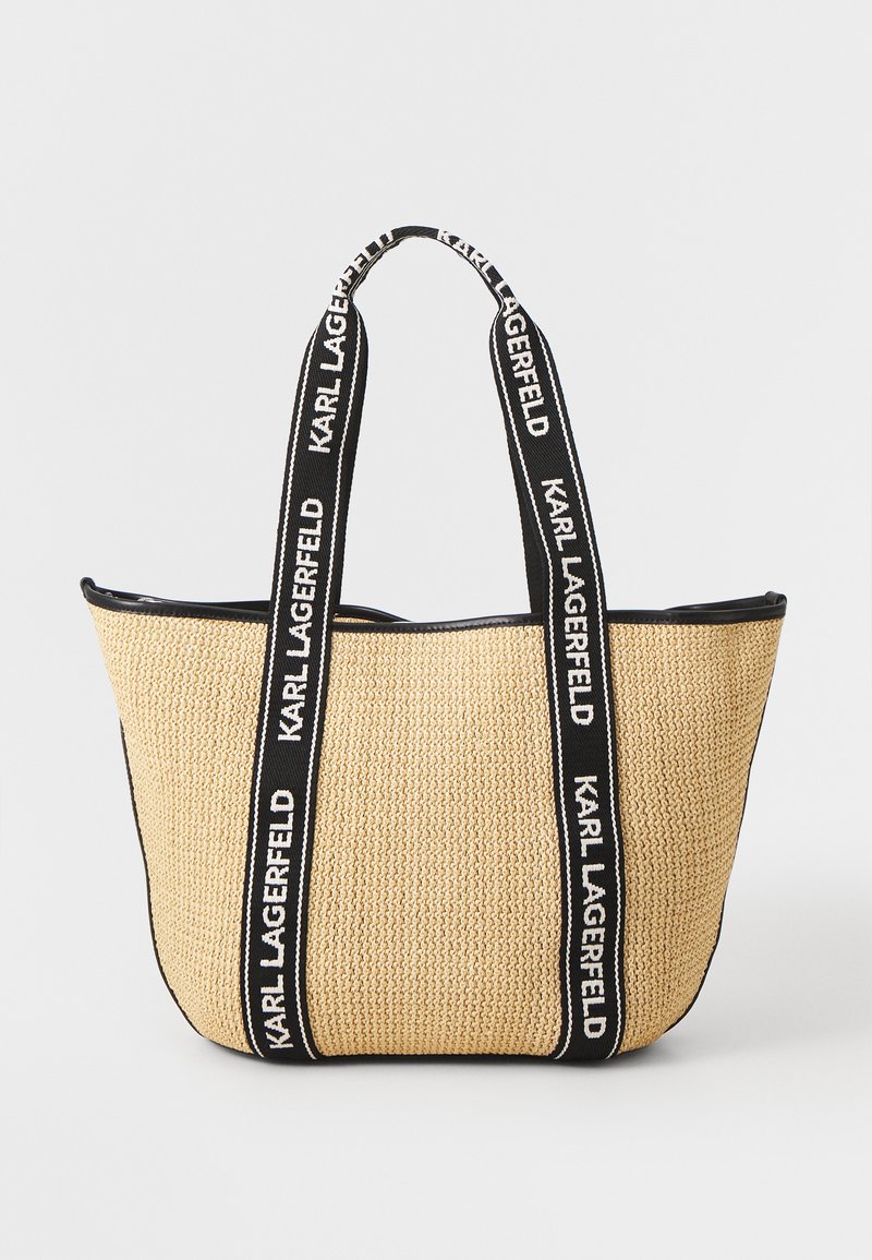 Große geflochtene Strohtasche mit schwarzen Stoffgriffen, die den Text "KARL LAGERFELD" zeigt. Rundliche Form, strukturierte Oberfläche und schwarzer Besatz.