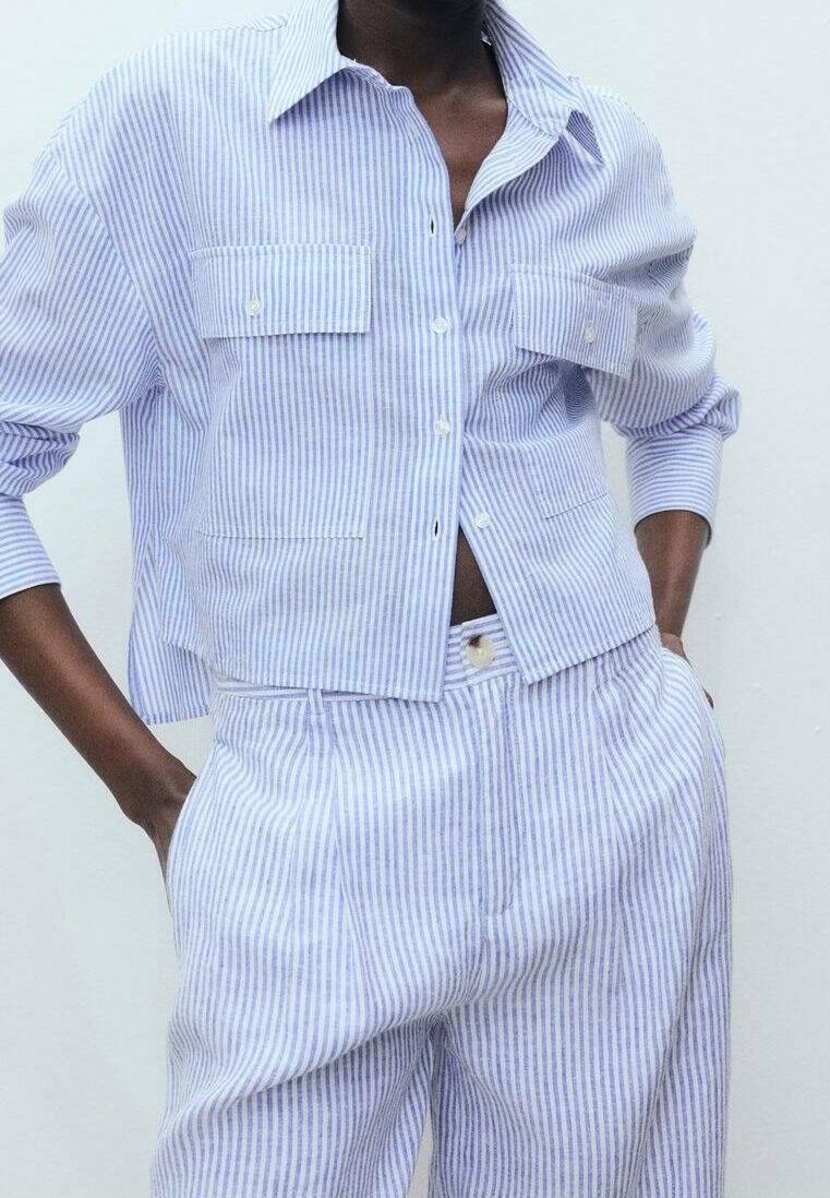 Chemise à rayures bleu clair et blanc avec deux poches poitrine, assortie à un pantalon sur mesure; tissu en coton, coupe décontractée.