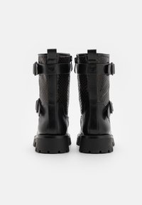 Bottines en cuir noir avec un motif serpent texturé, accents de boucles et semelle épaisse, dotées d'une fermeture éclair à l'arrière.