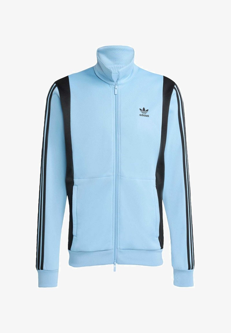 Veste zippée bleu clair en tissu texturé, avec des accents noirs et trois bandes noires le long de chaque manche. Comprend deux poches à l'avant.