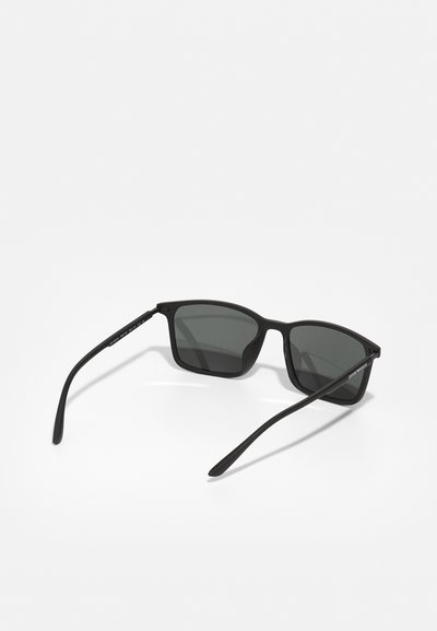 Ochelari de soare negri cu lentile închise, ramă rectangulară, material plastic neted, temple subțiri și branding subtil pe lateral.