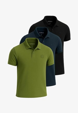 Trois polos exposés : vert foncé, marine et noir. Chacun a un col, des manches courtes et un logo brodé.