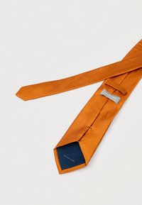 Pomarańczowy jedwabny krawat o gładkiej teksturze, z granatową podszewką wewnętrzną i srebrną metką z napisem „MICHAEL KORS”.