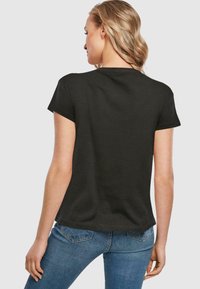 Svart kortermet t-skjorte med avslappet passform. Laget av bomull, med glatt tekstur og rund hals, kombinert med blå denimjeans.