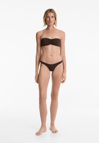 Rjavi bikini set, ki vključuje brezramni top z gubanjem spredaj in ujemajočim se nizkosedežnim dnom. Gladka tekstura, minimalističen dizajn.