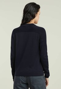 Maglione di lana navy con scollo a giro e maniche lunghe, con polsini e orlo a costine. Texture sottile e design semplice, senza decorazioni visibili.