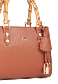 Bolso de piel marrón con asas de bambú, detalles de hardware en dorado y un sutil branding en relieve. Presenta un pequeño detalle de candado.