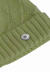 Zielona dziergana czapka z prążkowanym mankietem, ozdobiona teksturowanymi wzorami i okrągłą metaliczną naszywką z logo. Miękki akrylowy materiał.