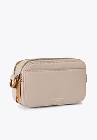 Sac bandoulière en cuir beige, forme rectangulaire, quincaillerie dorée, fermeture zippée, et une poche avant avec logo embossé.