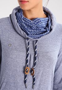 Grauer Hoodie mit Kapuze, ausgestattet mit einer blauen gemusterten Innenschicht, weißen Kordeln mit Holzakzenten an den Enden.