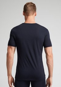 Námořnická modrá krátká rukávová trička vyrobená z měkké tkaniny, s kulatým výstřihem a přiléhavým střihem, s minimálními švy.