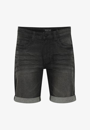 Čierne džínsy šortky s ohnutými okrajmi, ktoré majú päť vreciek, zapínanie na gombík a opotrebovaný vzhľad. Na štítku je napísané "INDICODE."