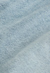 Ljusblå denimtyg med en slät textur, som har ett subtilt, enhetligt väv och små variationer i nyans över ytan.