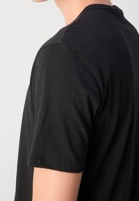 Sort bomulds t-shirt med korte ærmer, rund halsudskæring og en glat tekstur. Bemærkelsesværdige detaljer inkluderer pæne syninger og en afslappet pasform.