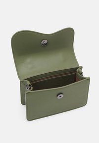 Zielony skórzany portfel z zaokrągloną klapką, zapięciem na zatrzask i kontrastową, wewnętrzną podszewką. Charakteryzuje się gładką fakturą i minimalistycznym designem.