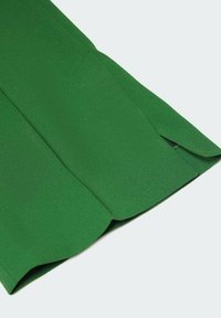 Green fabric with a smooth texture, featuring a flared design. The hem has a subtle slit detail, enhancing its overall shape.