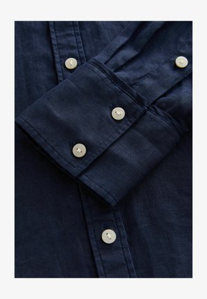 Navy blue linen shirt with a buttoned cuff, featuring four round, light-colored buttons and a smooth, textured fabric.