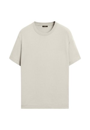 Hellbeiges T-Shirt mit kurzen Ärmeln und Rundhalsausschnitt, mit einem schwarzen Etikett auf der Innenseite des Rückenkollars, präsentiert vor weißem Hintergrund.