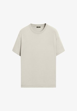 Lichtbeige T-shirt met korte mouwen en ronde hals, met een zwart label aan de binnenkant van de achterkraag, weergegeven tegen een witte achtergrond.