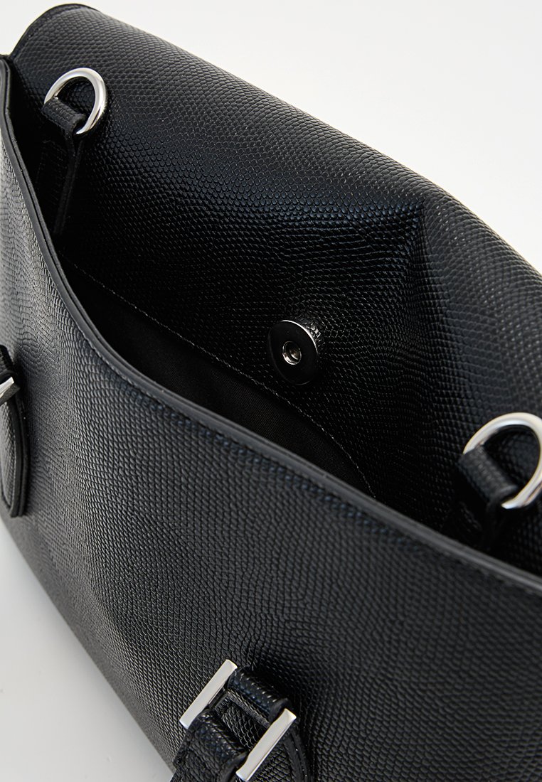 Intérieur d'un sac à main en cuir texturé noir, avec une fermeture à pression magnétique, des accents en métal argenté et un doublure lisse noire.