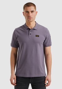 Muška polo majica u purpurnoj boji, izrađena od pamuka. Ima klasični ovratnik, placket sa tri dugmeta i logotip na prsima. Kratki rukavi.