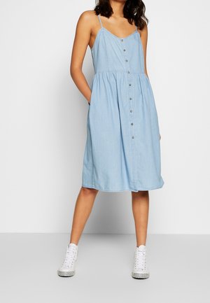 Lichtblauwe denim jurk met dunne bandjes, een knoopsluiting aan de voorkant en een uitlopende rok. Heeft zijzakken en een ontspannen pasvorm.