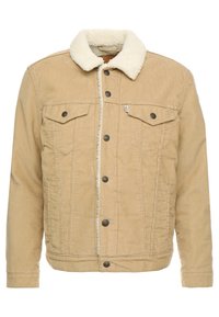 Beige kordjacka med vit sherpa-krage, knappstängning fram, två bröstfickor med klaff och sidofickor för händerna.