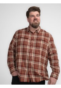 Geruite overhemd in bruin, oranje en crème tinten. Twee borstzakken met kleppen, lange mouwen en een kraag. Zachte textuur.