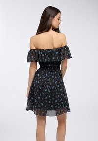 Abito nero senza spalle con scollo arricciato, vita elastica e piccola stampa floreale blu su tessuto trasparente. Lunghezza corta, texture leggera.