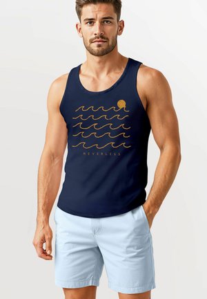 Navy tank top featuring a gold octopus and wavy line graphic. Made of fabric with a smooth texture. Paired with light blue shorts.